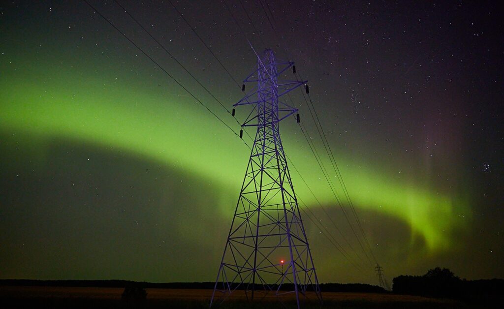 Green aurora arc curving behind a hydro tower