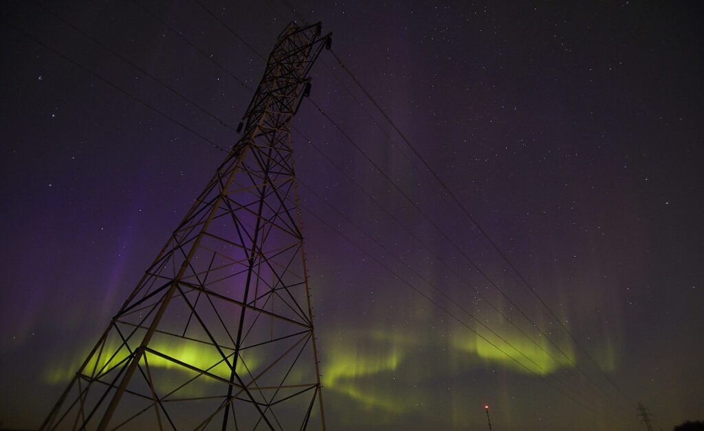 Purple aurora with a green glow behind a hydro tower