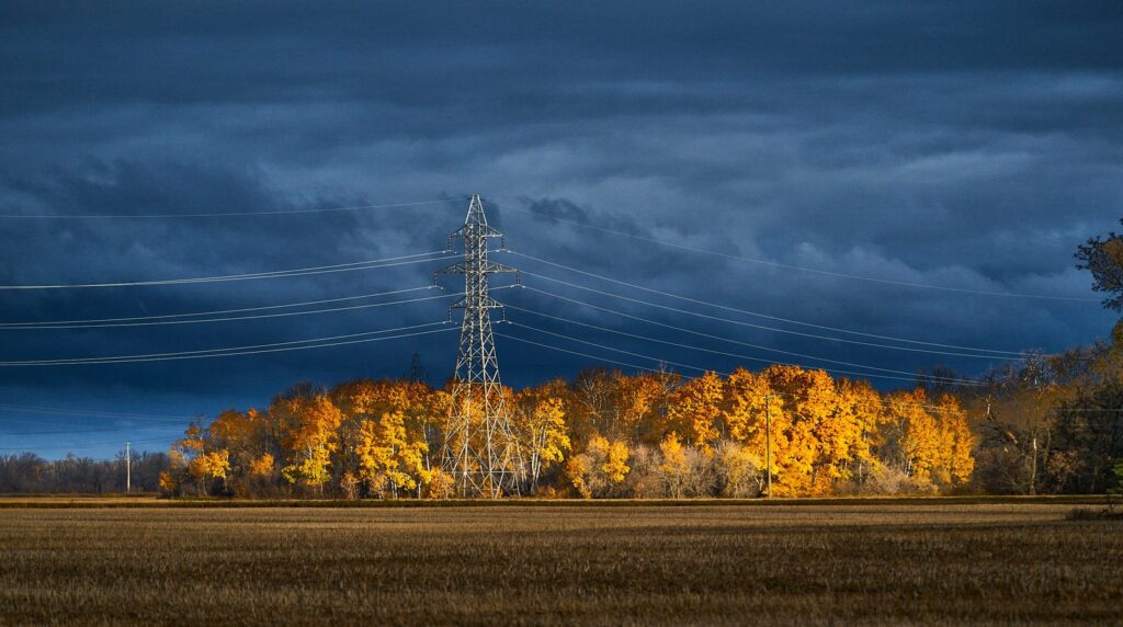 Golden aspen bluff beneath a hydro tower and dark storm clouds