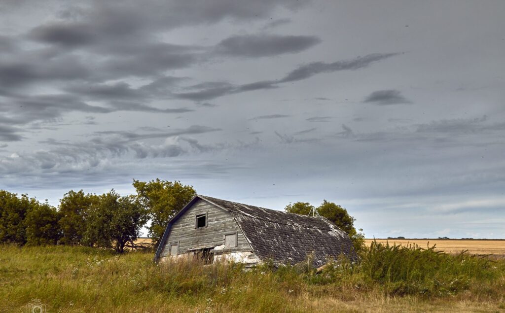 Sagging old barn in a green field under broken cloud