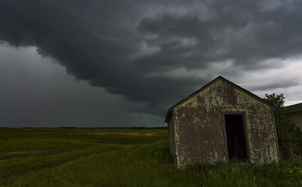 Weathered granary beneath a dark shelf cloud