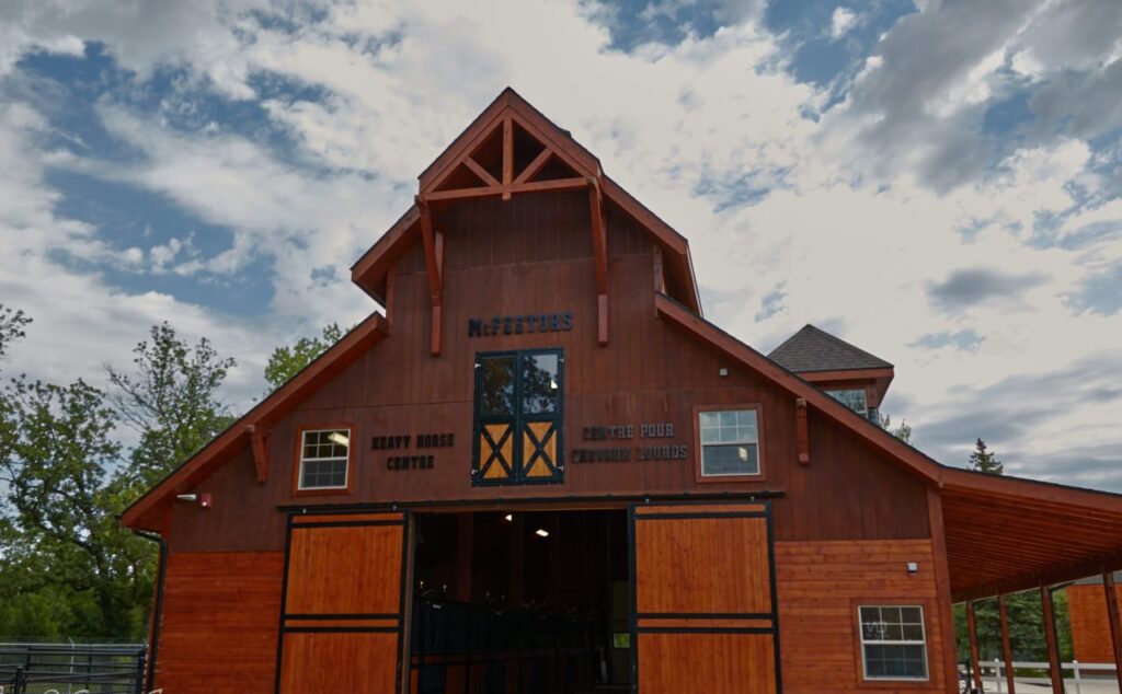 Large red barn with open doors under blue sky and cloud