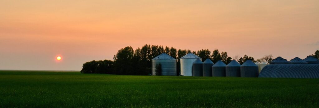 Row of grain bins on the horizon at sunset