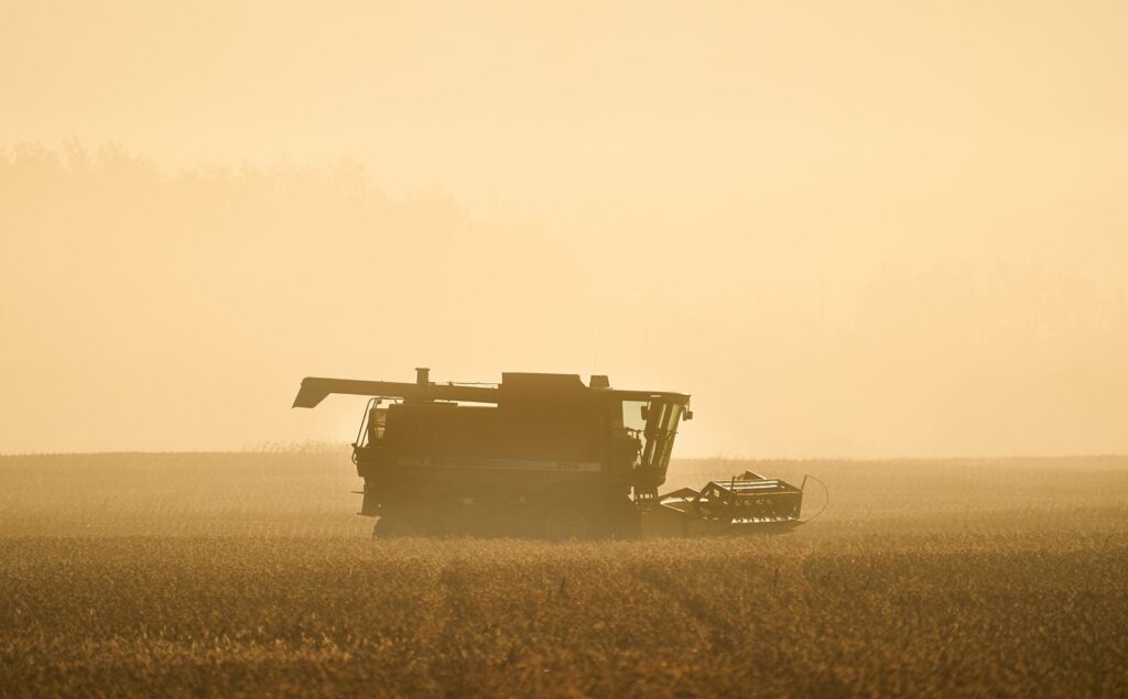 Combine harvesting in a field through golden haze