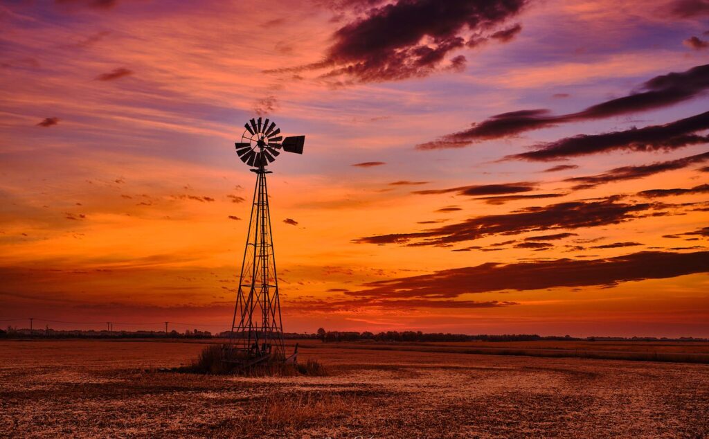 Prairie windmill silhouetted against a red and purple sunset
