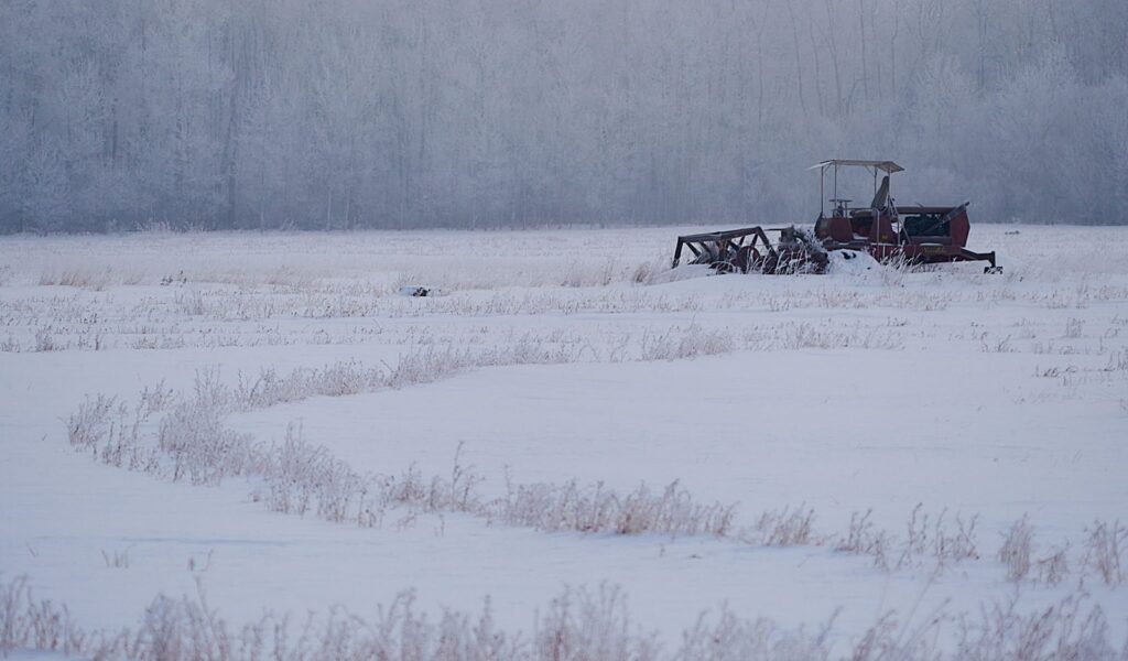 Old swather abandoned in a snowy field