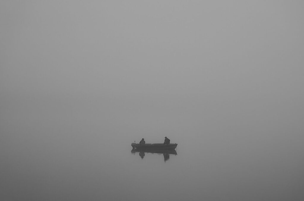 Fishing boat on a river in thick grey fog