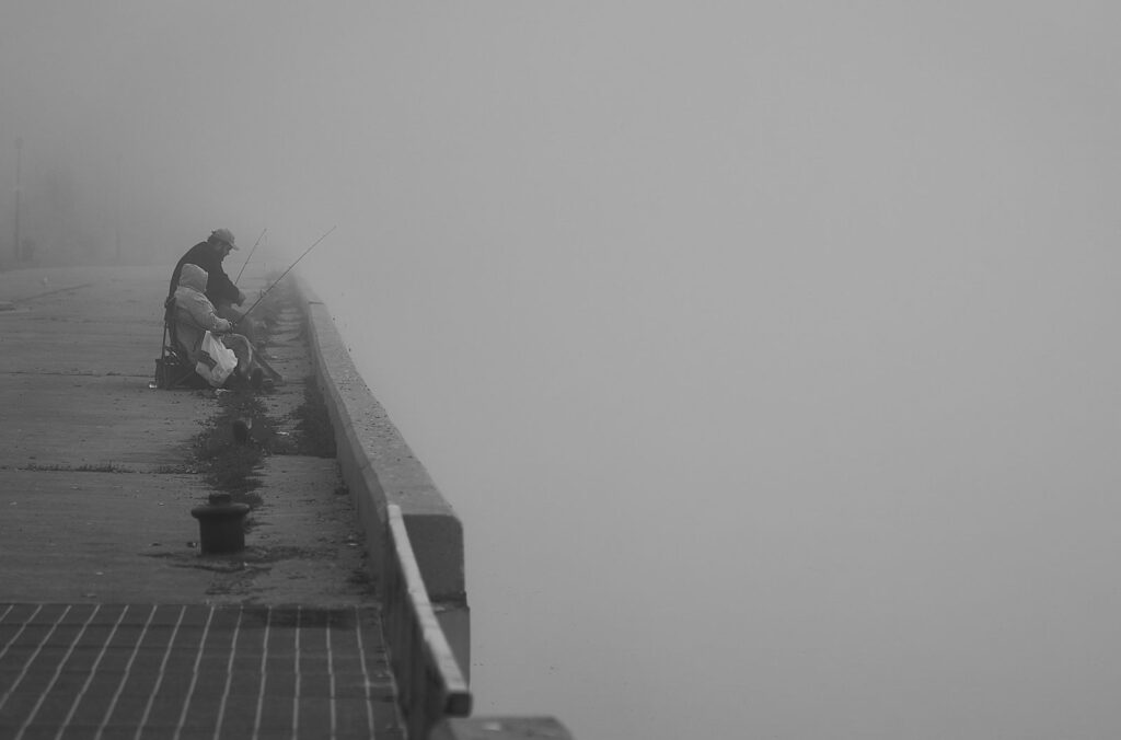 Angler on a pier in dense fog