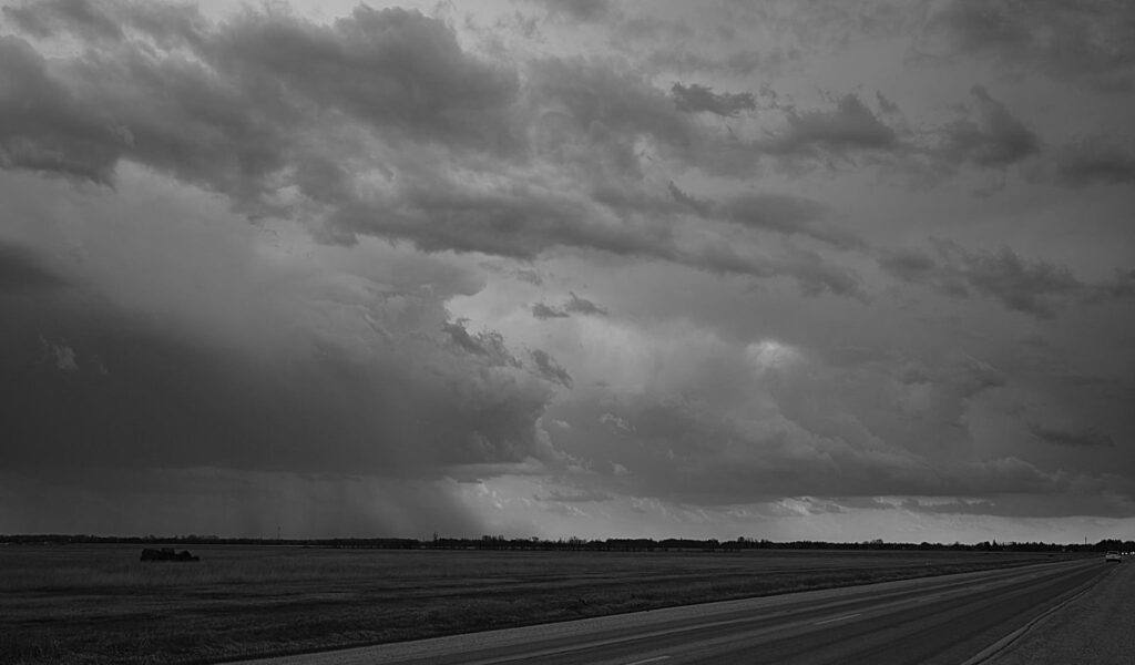 Rain falling from a heavy sky over a prairie highway