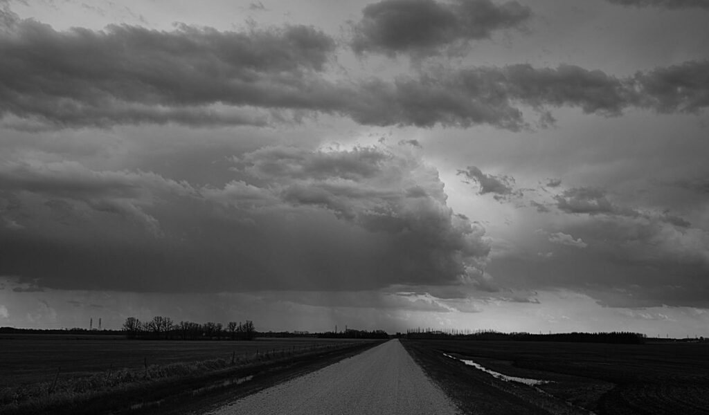 Storm clouds building over a straight gravel road