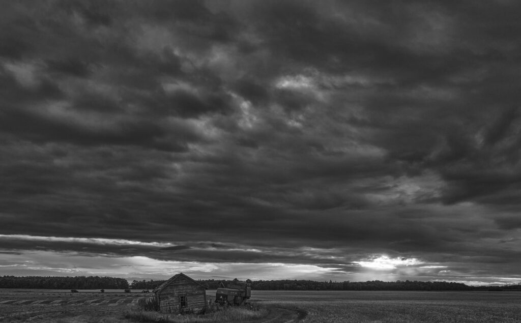Low dark clouds over an old farmhouse on the prairie