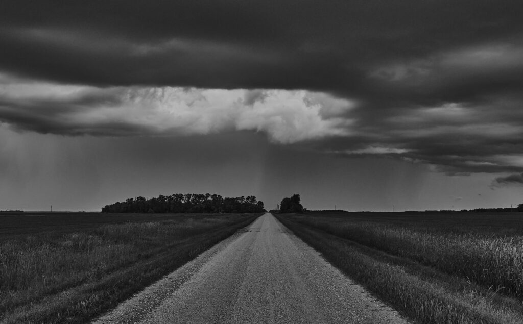 A long gravel road under a dark band of cloud
