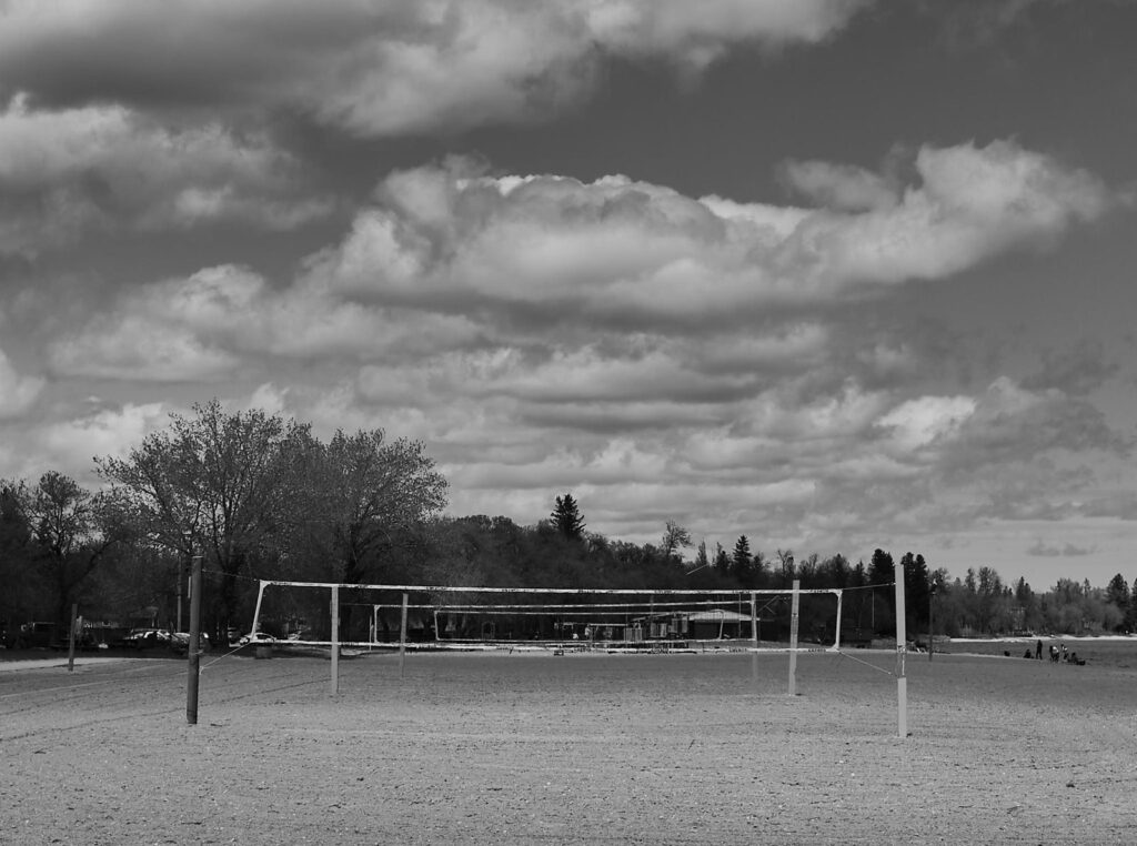 Fluffy clouds over a sports field and trees