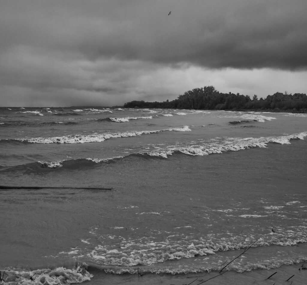 Waves rolling onto a shore under a grey sky