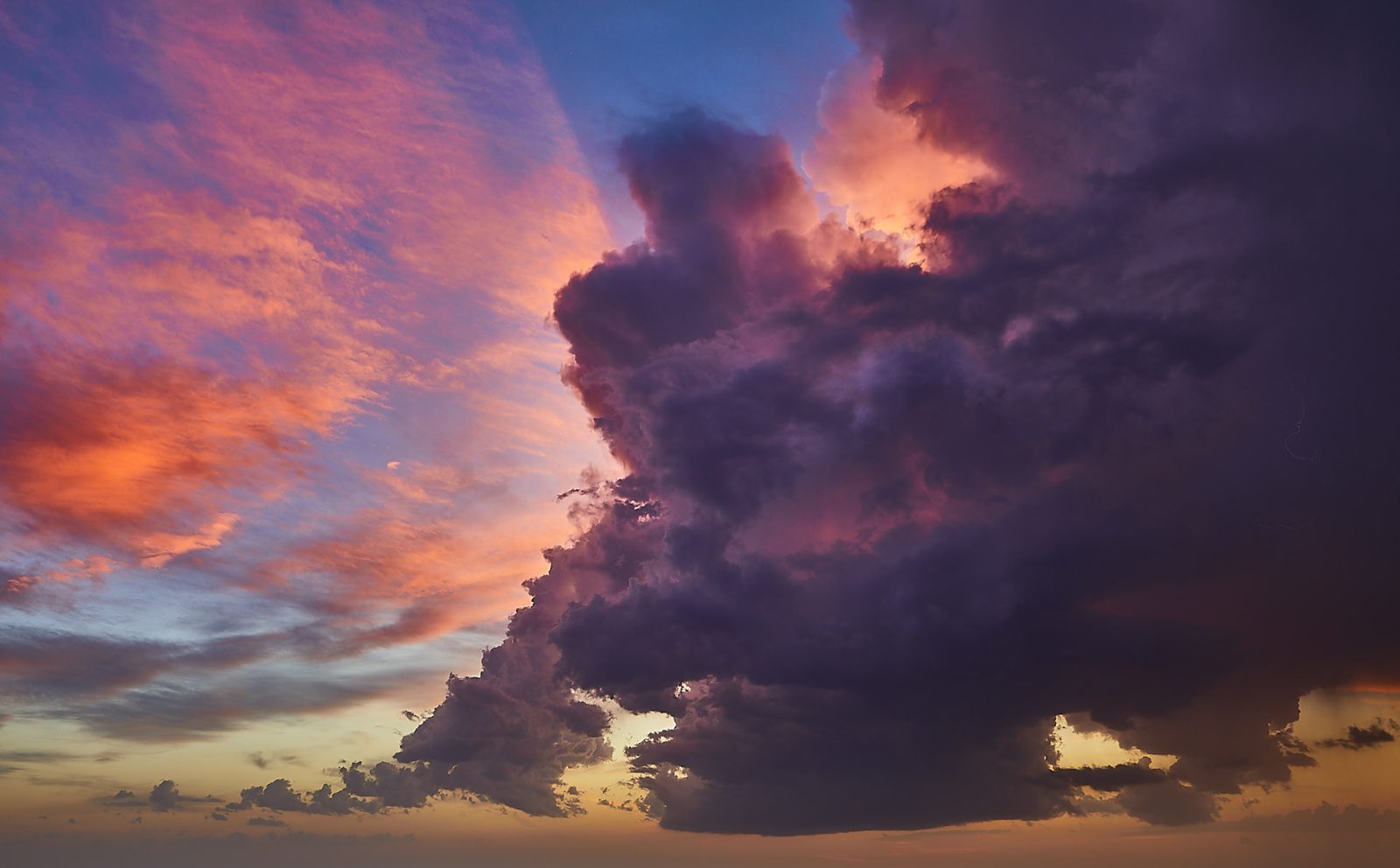 Purple thunderhead lit pink and orange by the setting sun