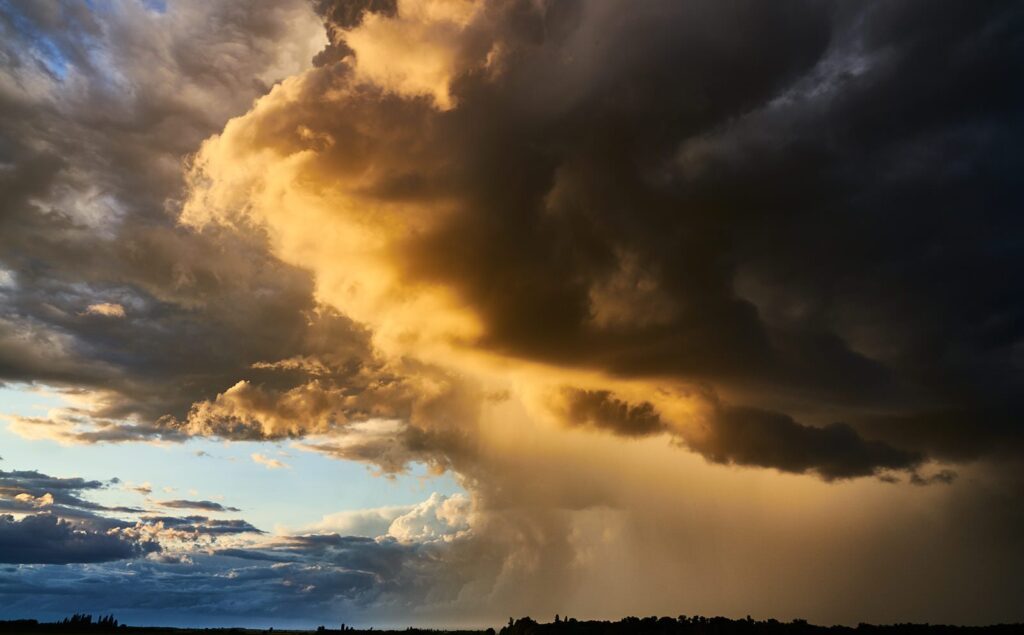 Golden light breaking through dark storm clouds with rain falling