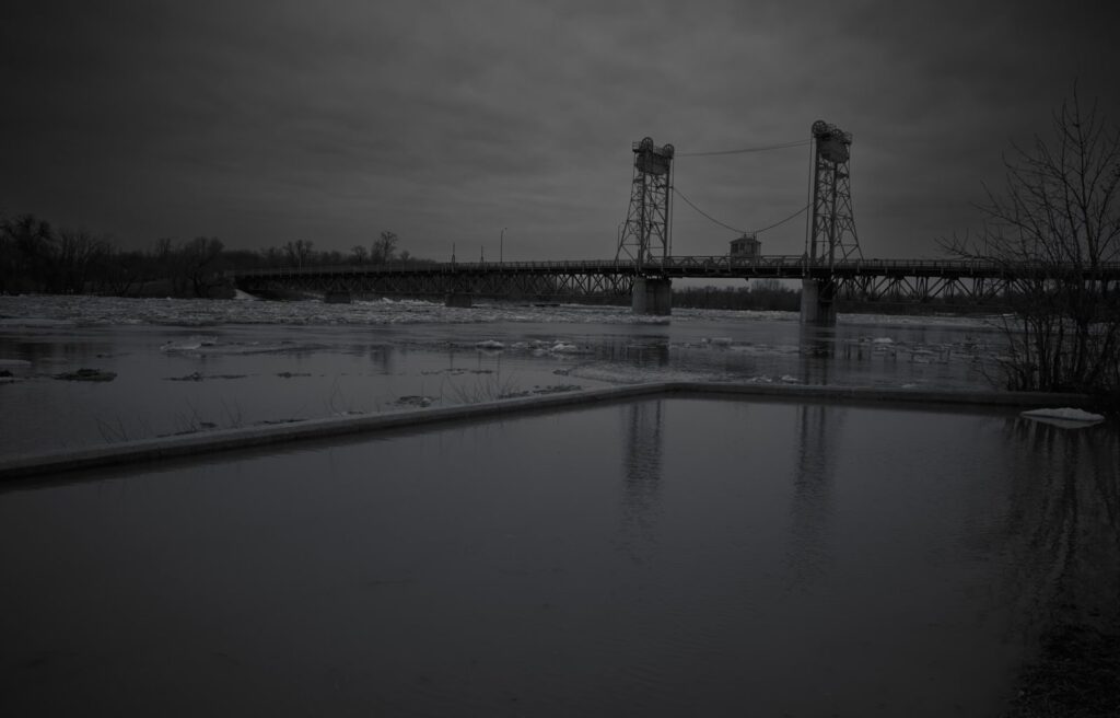 Lift bridge over a flooded river, reflected in still water