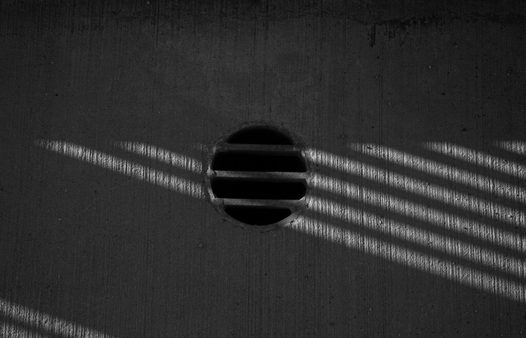 Round slatted vent in a concrete wall with stripes of shadow
