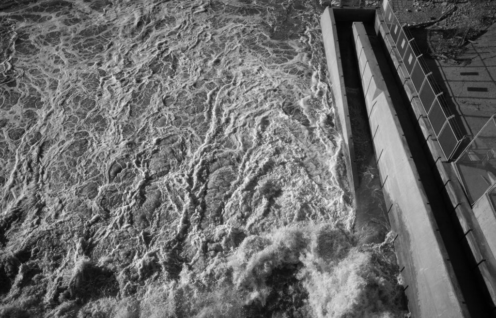 Churning water in a concrete spillway channel seen from above
