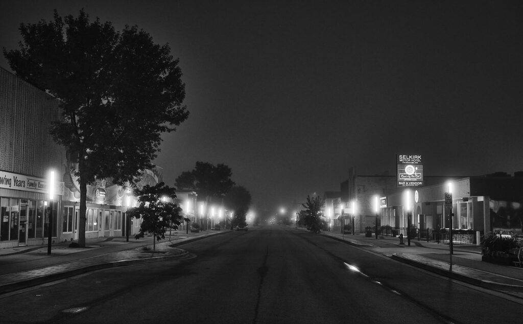 Main street at night with glowing streetlights and shop signs