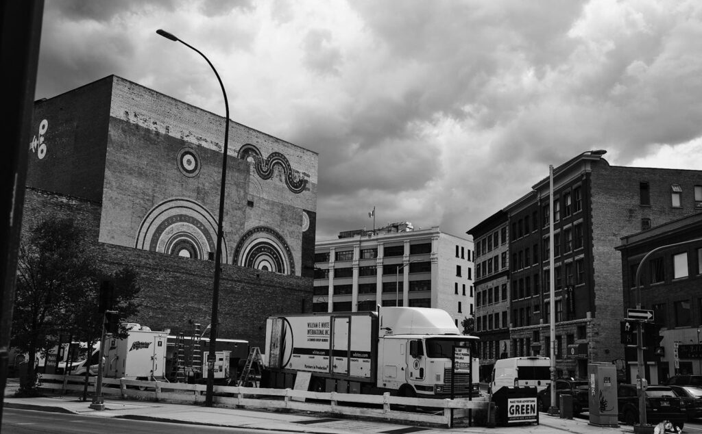 Large circular mural on a building at a downtown corner, with a delivery truck