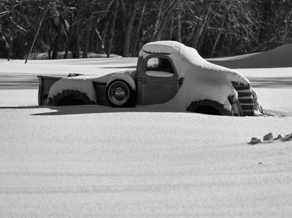 Old pickup truck buried in deep snow