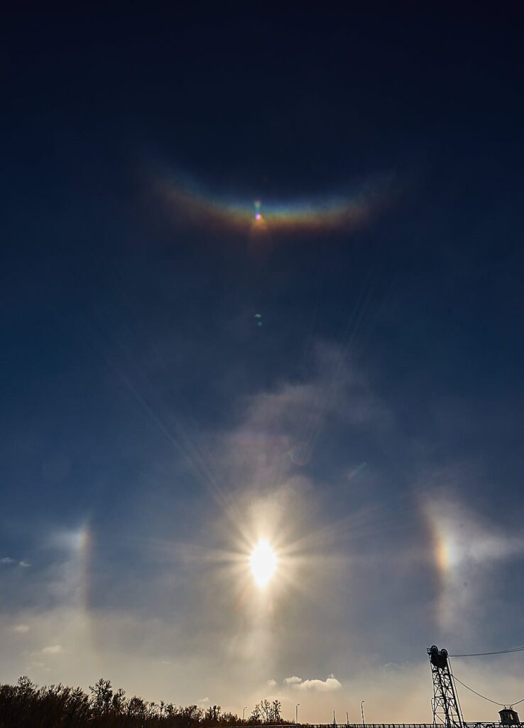 Sun dogs flanking a low winter sun above a snowy road