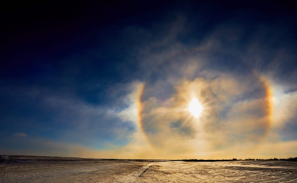 Wide halo and sun dogs around the sun over snow-covered prairie