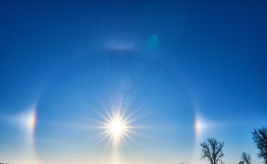 Starburst sun with sun dogs and a faint halo above a snowy field
