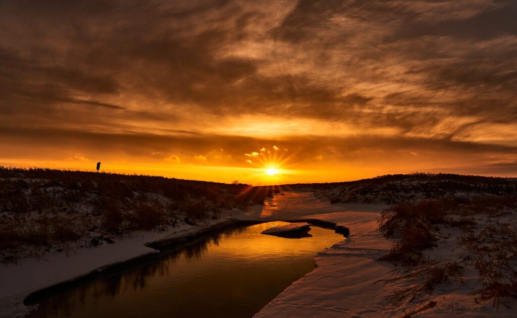 Winter sun setting over a snowy creek