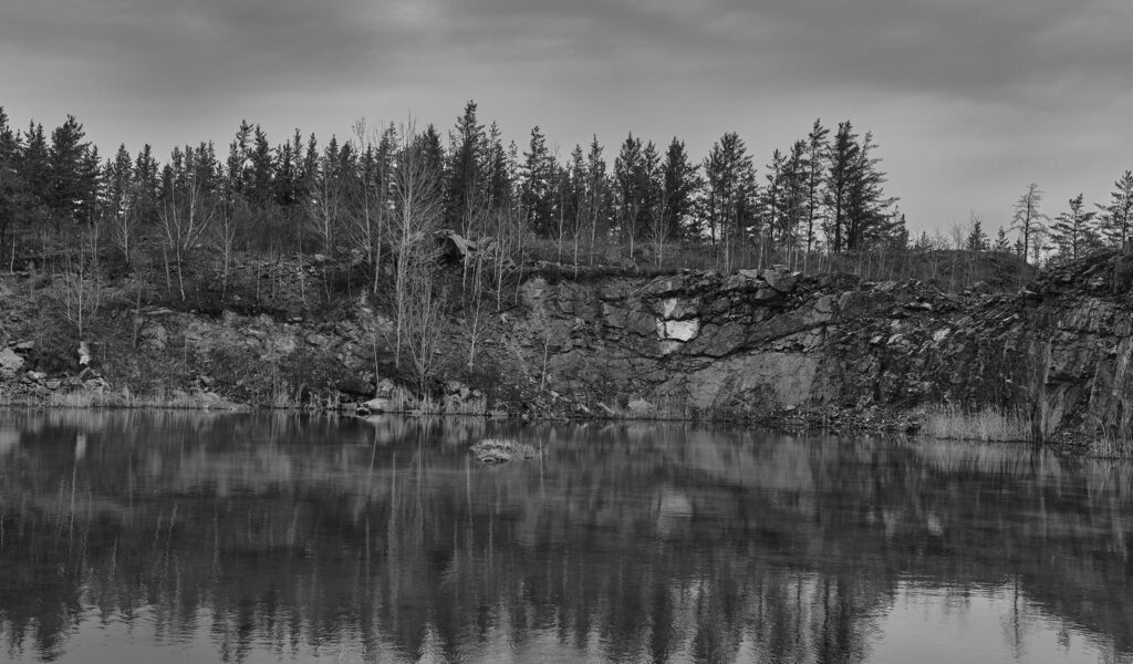 Rock bluff and spruce forest reflected in a still northern lake