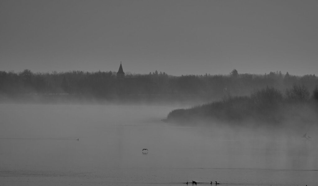 Mist over a river with a distant church steeple