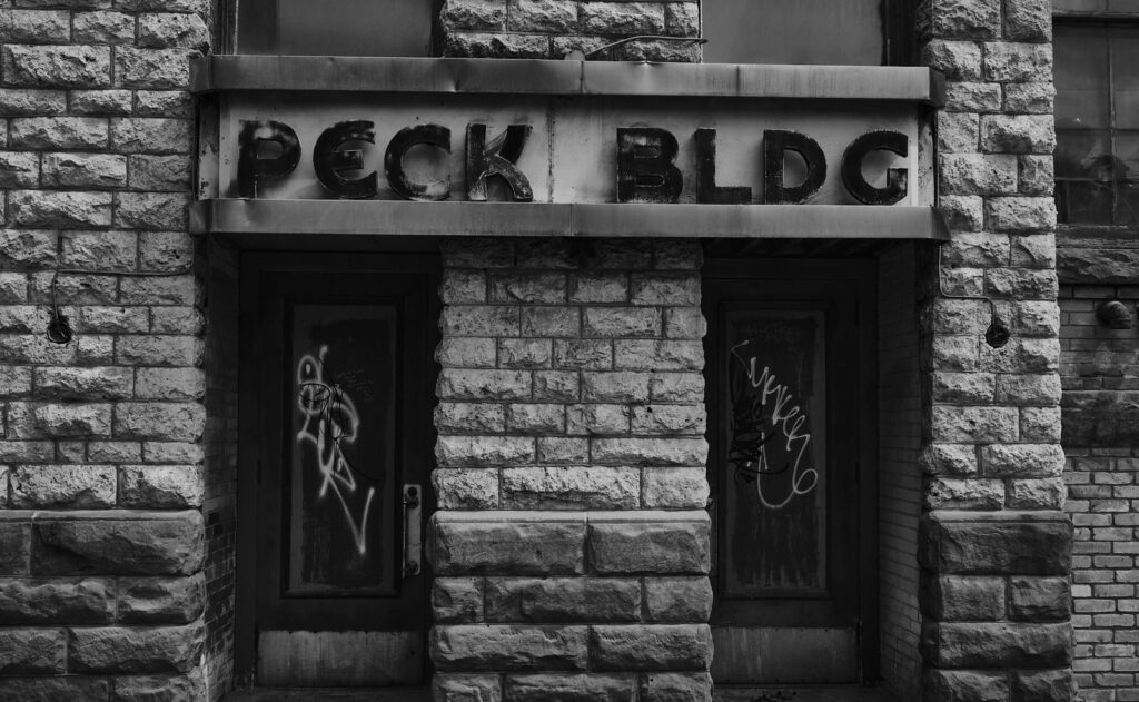 Stone-faced building with a faded Peck Bldg sign