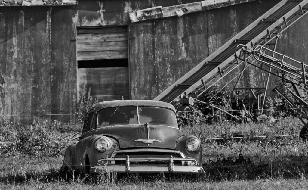 Old car parked in front of a weathered granary