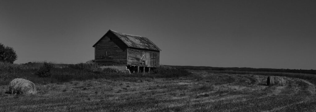 Weathered farm building on a dark prairie hill