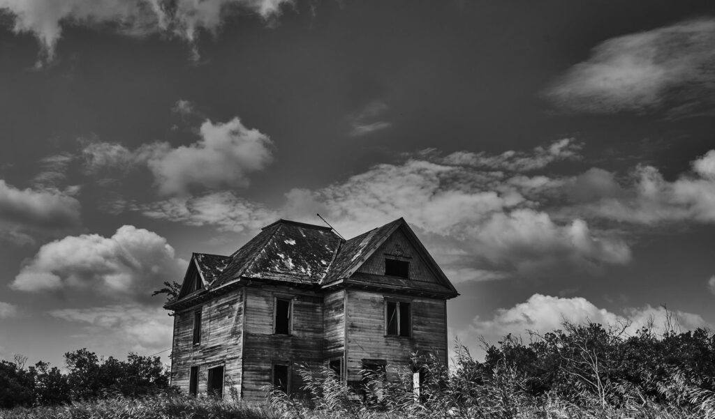 Abandoned two-storey farmhouse under a big sky